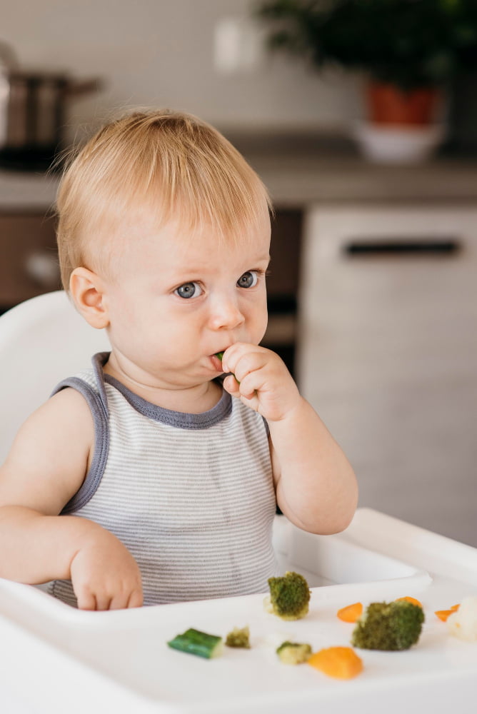 Baby eating food at the table as a family